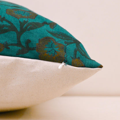 Teal wild rose block print linen cushion cover on a sofa